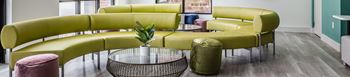 A green sofa with a glass table in front of it.